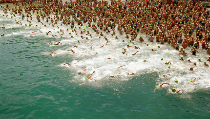 Тысячи людей в зеленых шапочках, участвуют в ежегодном заплыве