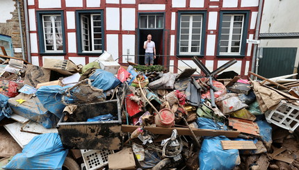 Мужчина у дома в районе, пострадавшем от наводнения, вызванного сильными дождями, в Бад-Мюнстерайфеле, Германия.