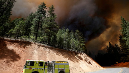 Пожарная машина проезжает мимо столбов темного дыма у  лесного пожара недалеко от города Гринвилл, Калифорния, США.