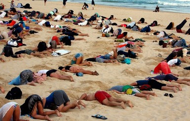 На пляже Австралии сотни людей сунули головы в песок