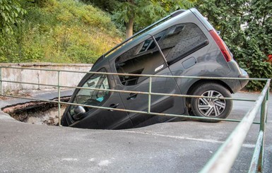 В Киеве машина провалилась в огромную яму посреди дороги