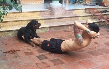 Собака вьетнамца держит его ноги, пока тот качает пресс