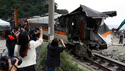 Люди фотографируют поврежденный вагон поезда, извлеченный из туннеля после крушения поезда к северу от Хуаляня, Тайвань.