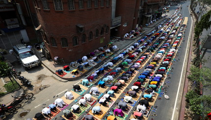 Мусульмане принимают участие в пятничной молитве в рамках священного месяца поста Рамадан на улице перед мечетью 