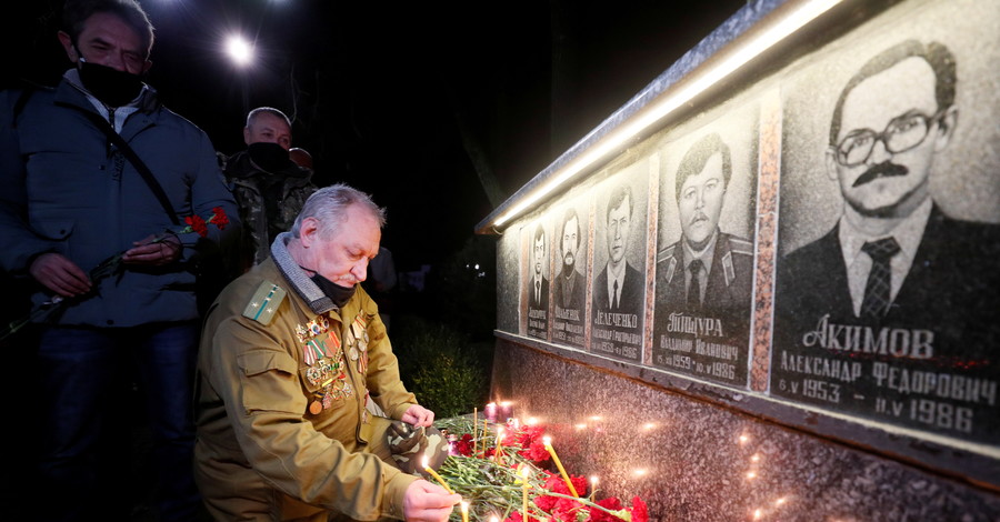 Мужчина зажигает свечу у мемориала, посвященного пожарным и рабочим, погибшим после аварии на Чернобыльской АЭС, в Славутиче, Ук