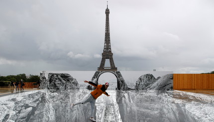 Мужчина позирует на гигантском произведении французского художника JR, установленном на площади Трокадеро перед Эйфелевой башней