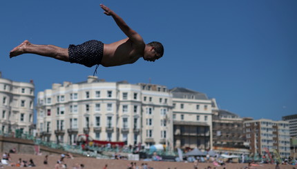 Люди наслаждаются жаркой погодой на пляже Брайтон в Брайтоне, Великобритания.
