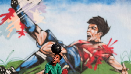 Ребенок играет в футбол на улице в районе Кейландия в Бразилиа, Бразилия