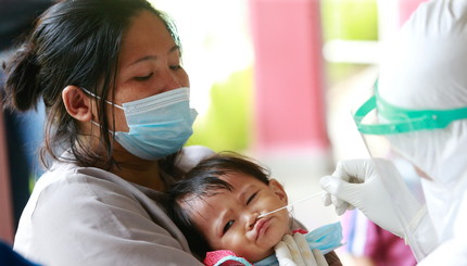 Фавзия, годовалый младенец, реагирует на то, как медицинский работник берет образец мазка для проверки на коронавирусную болезнь