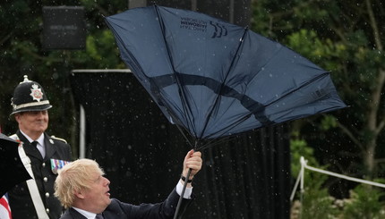 Премьер-министр Великобритании Борис Джонсон борется с зонтиком во время посещения Национального мемориального дендрария в Алрев