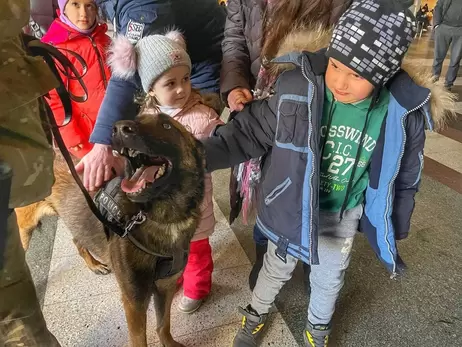 Кинологи с собаками развлекают детей на вокзале, чтобы помочь пережить стресс