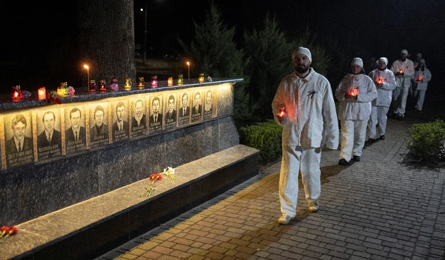 Сотрудники Чернобыльской АЭС несут свечи к мемориалу