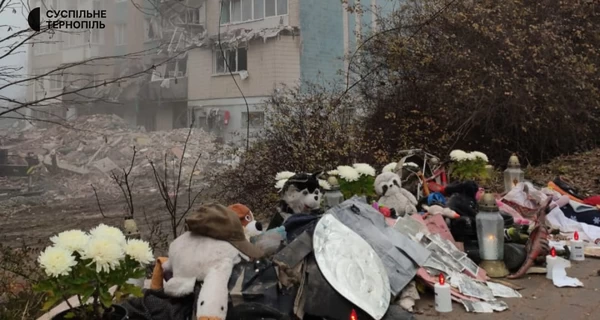 У Тернополі люди несуть квіти та іграшки до будинку, зруйнованого російською ракетою