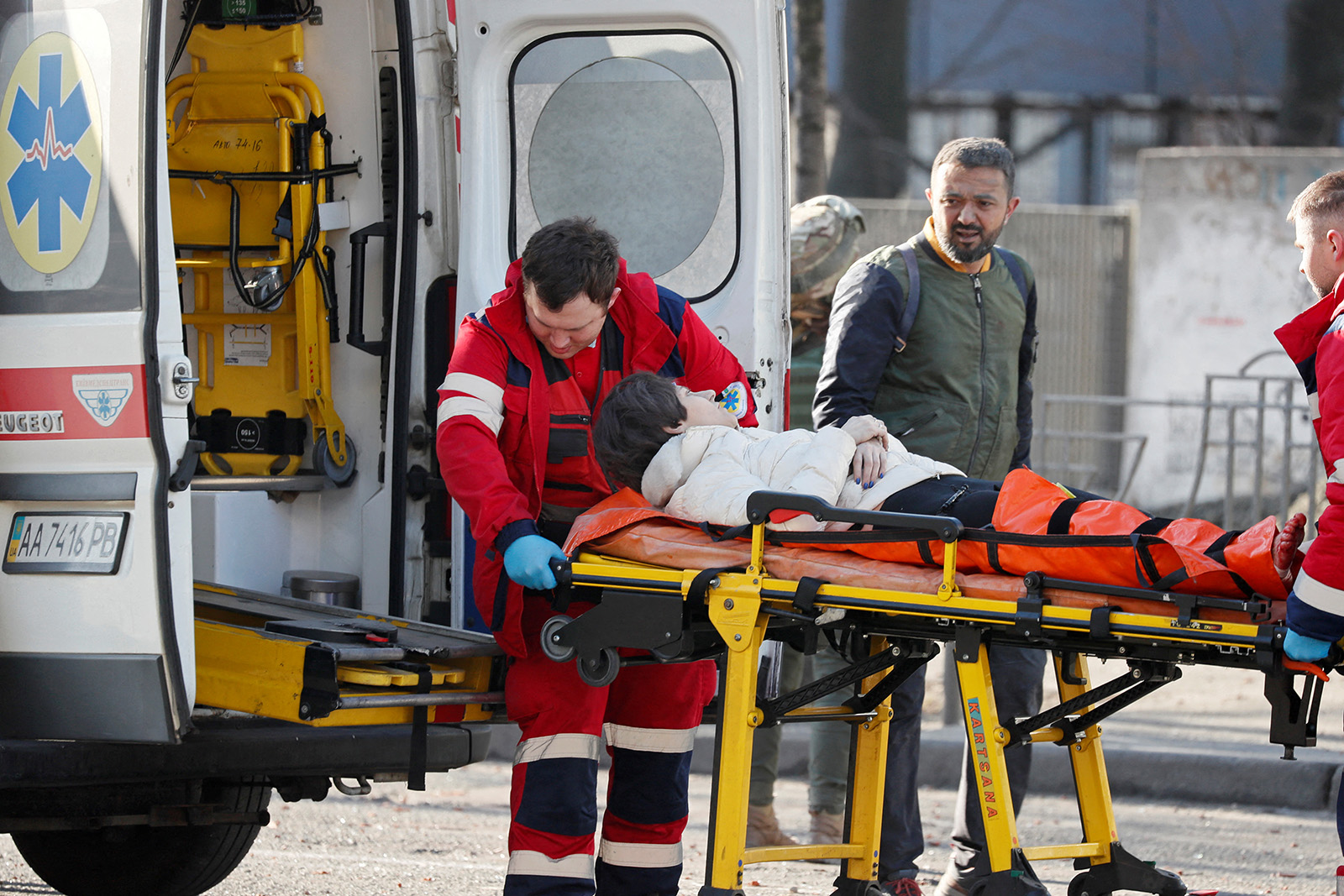 Медики везуть жінку, яка була поранена під час обстрілу житлового будинку, в машину швидкої допомоги, поряд стоїть її чоловік, Київ, Україна 26 лютого 2022 р. Фото: REUTERS/Gleb Garanich